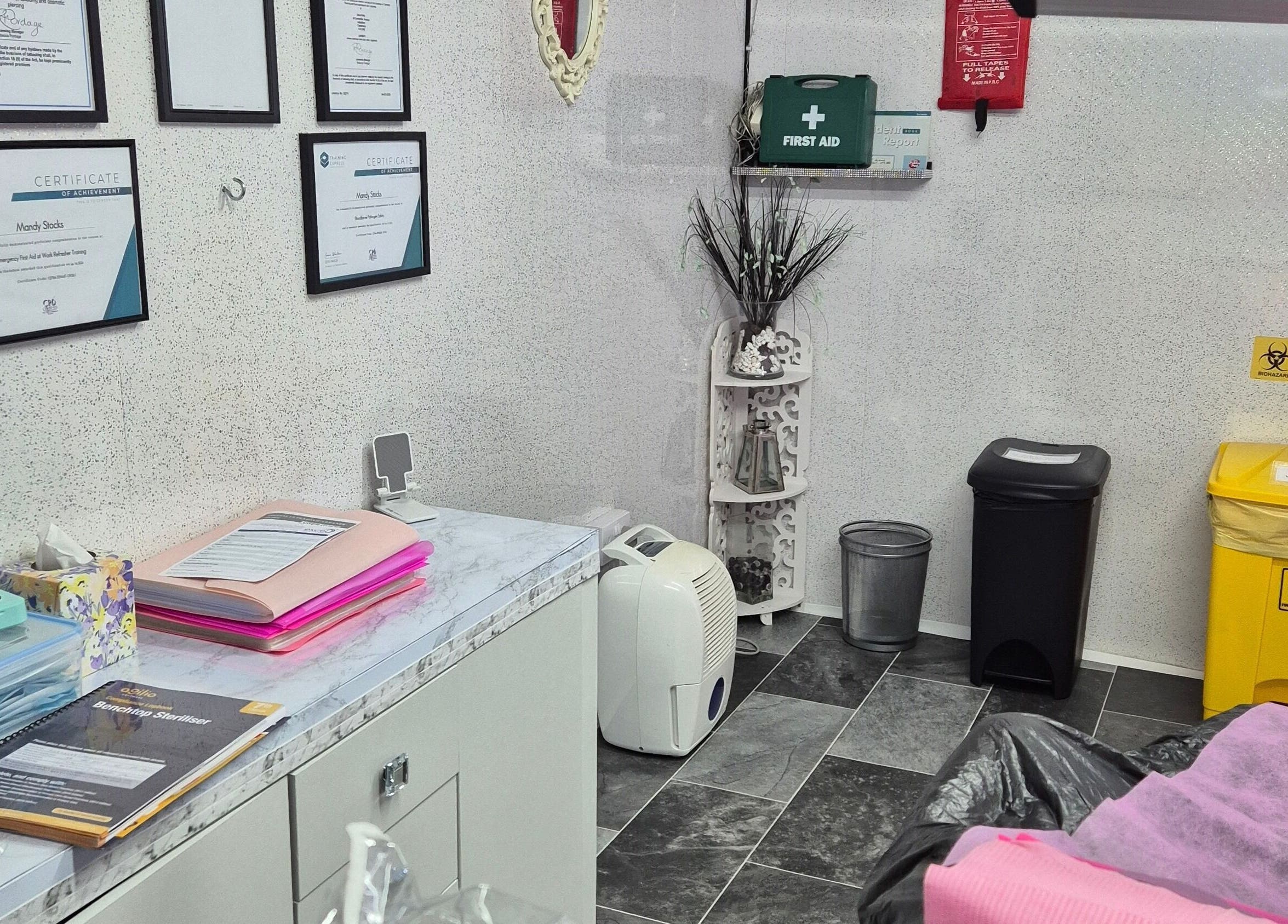 Skin-Finity treatment room in Aylesham, England, featuring certificates and essential supplies.