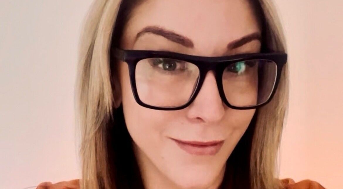 Smiling woman with glasses at Tres Beaux Aesthetics in Birmingham, England, GB.