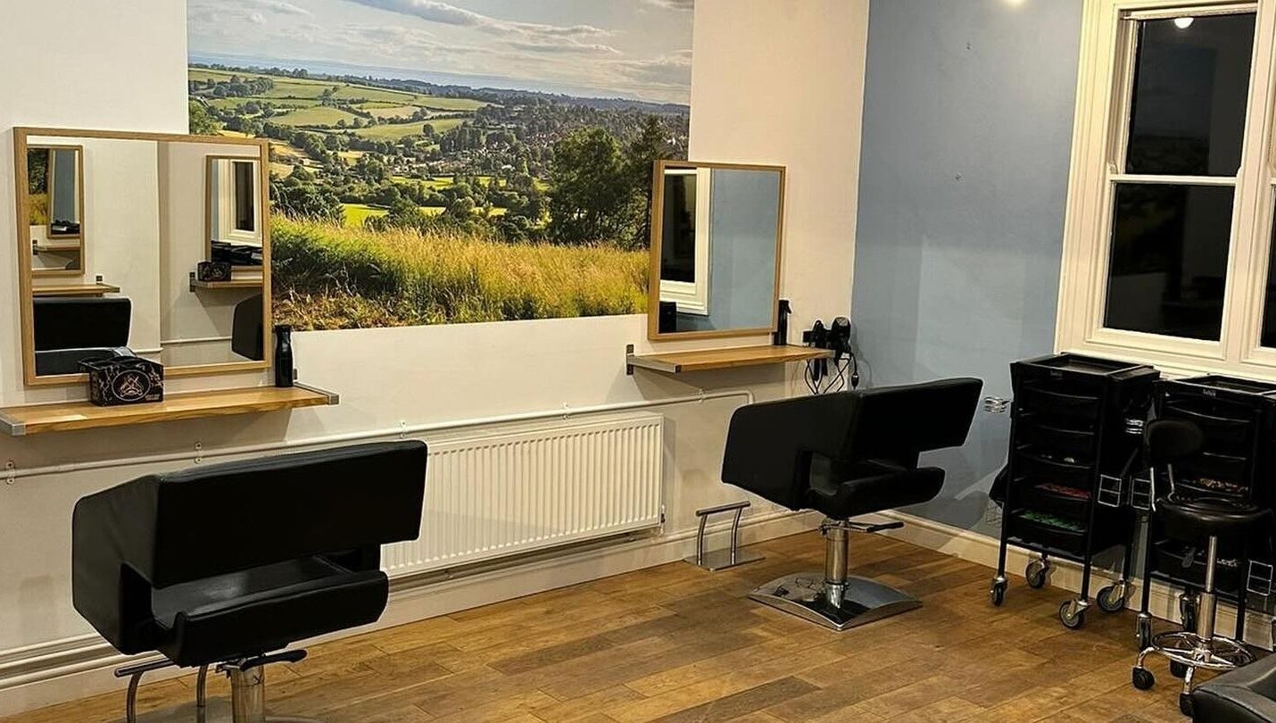Modern salon interior at Whites Hairdressing in Bromyard, England, GB, featuring stylish chairs and scenic wall art.