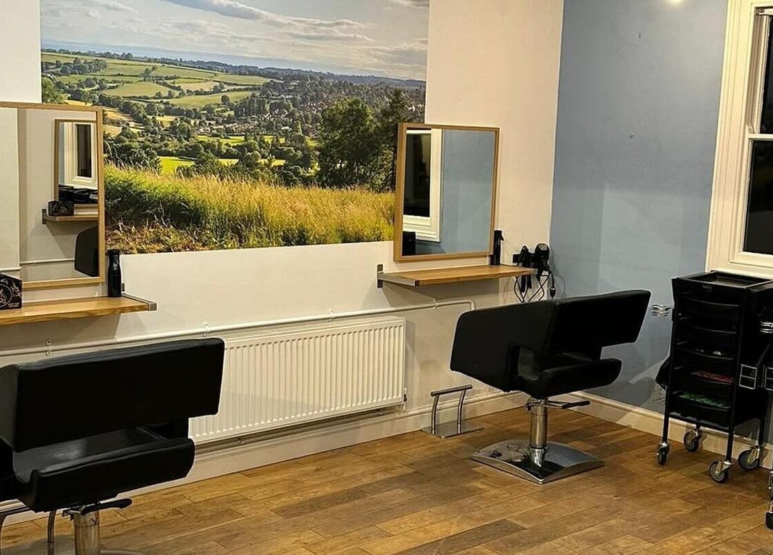 Modern salon interior at Whites Hairdressing in Bromyard, England, GB, featuring stylish chairs and scenic wall art.