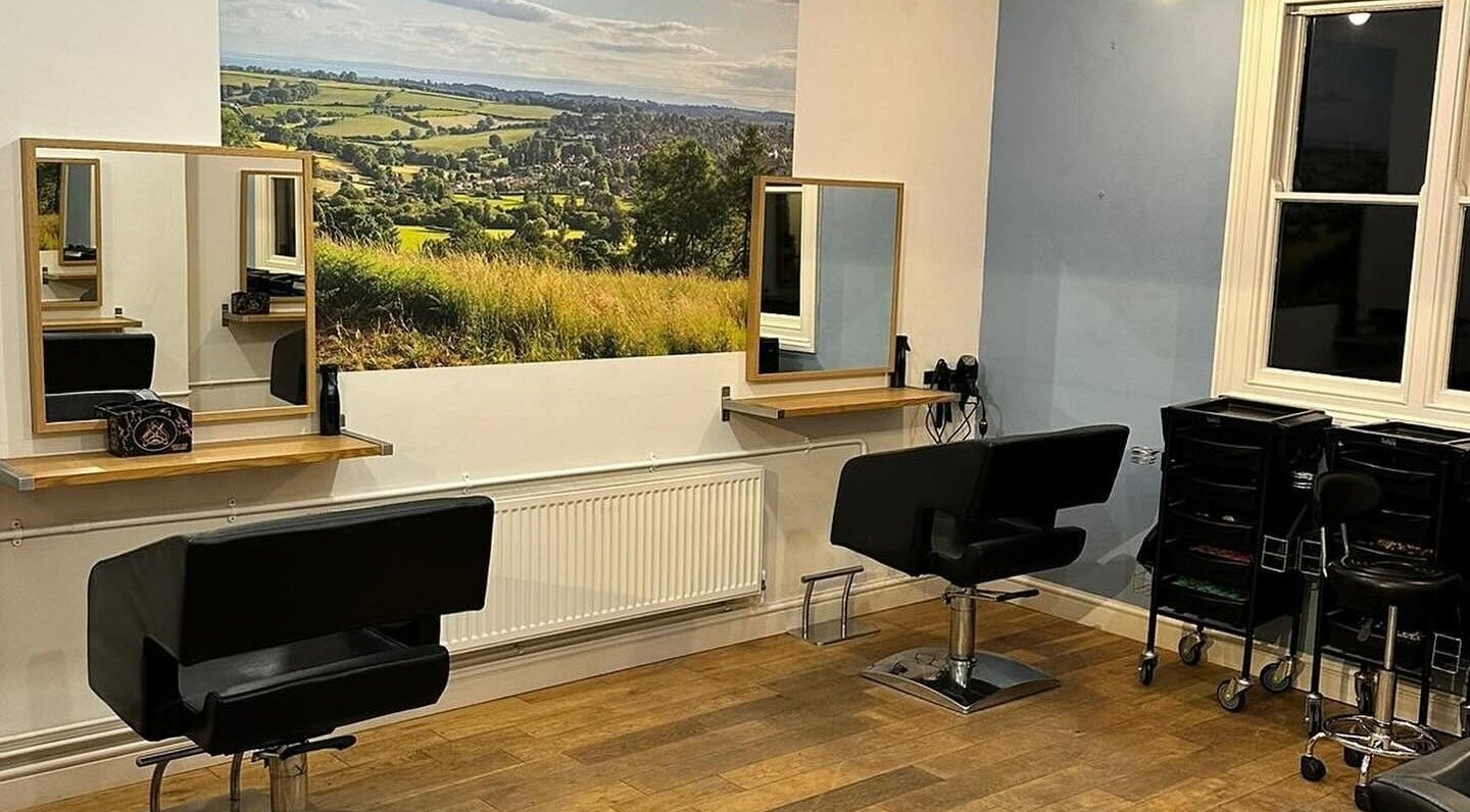 Modern salon interior at Whites Hairdressing in Bromyard, England, GB, featuring stylish chairs and scenic wall art.