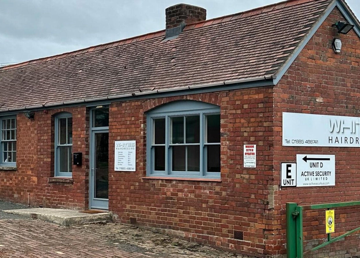 Whites Hairdressing exterior in Bromyard, England with vintage brickwork and modern signs.