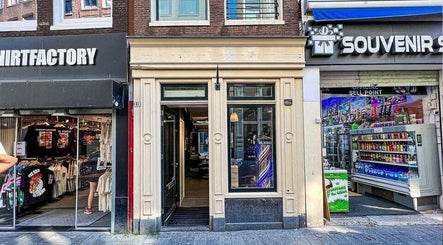 Entrance of Prime Barbershop Amsterdam, nestled between shops in Amsterdam, Noord-Holland, NL.