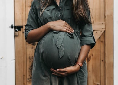 Pregnant woman cradling belly at Alma Wellness, West Wickham, England, GB.