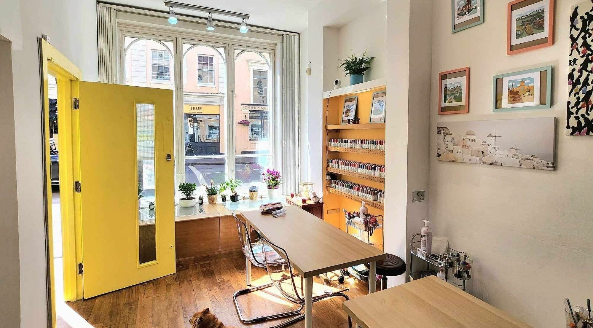 Cozy interior of The Nail Garden Greenwich, London, England, GB with vibrant yellow door and nail polish display.