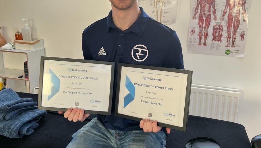 Certified therapist at Ryan Farr Sports Massage Therapy in Moira, Northern Ireland showcasing completion certificates.
