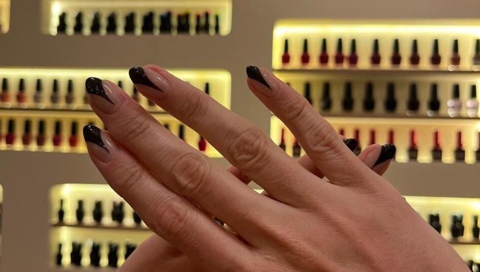 Manicura elegante en Cactus Lomas, Ciudad De México, con fondo de esmaltes en exhibición.