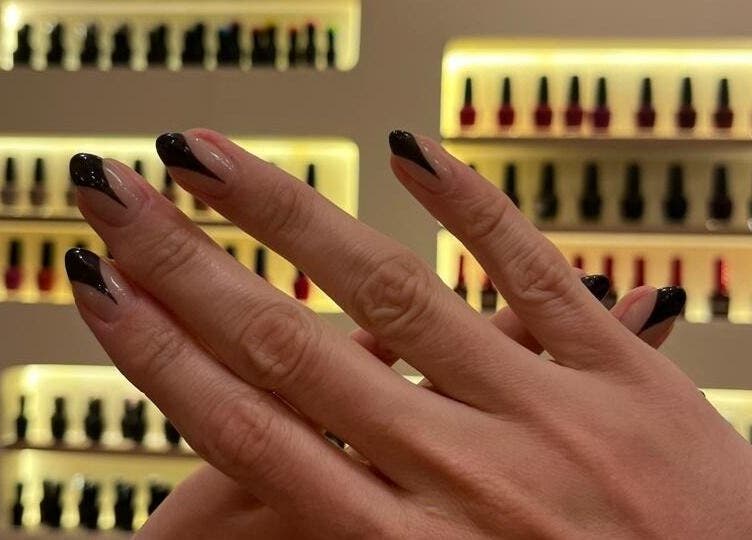 Manicura elegante en Cactus Lomas, Ciudad De México, con fondo de esmaltes en exhibición.