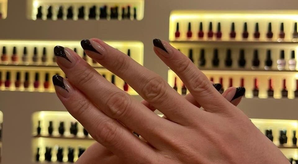 Manicura elegante en Cactus Lomas, Ciudad De México, con fondo de esmaltes en exhibición.