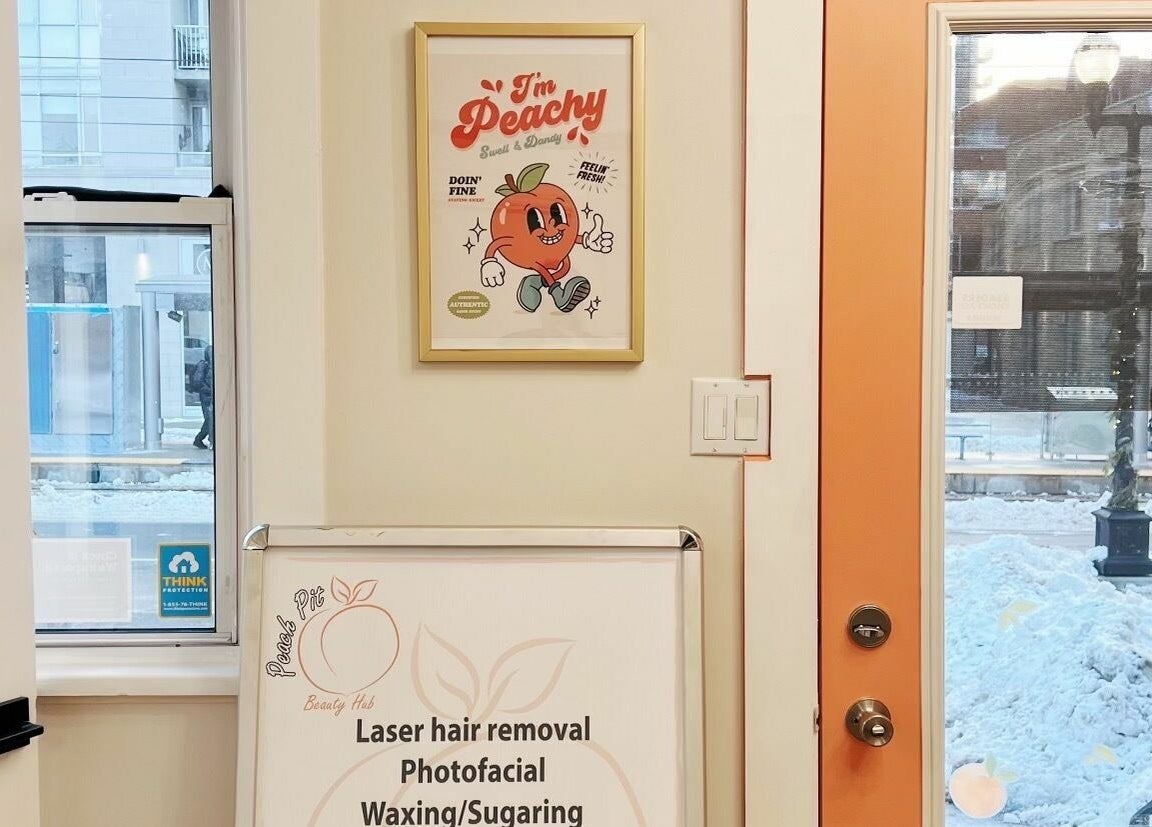 Front entrance of Peach Pit Beauty Hub in Waterloo, Ontario, CA, featuring a fun peach-themed poster.
