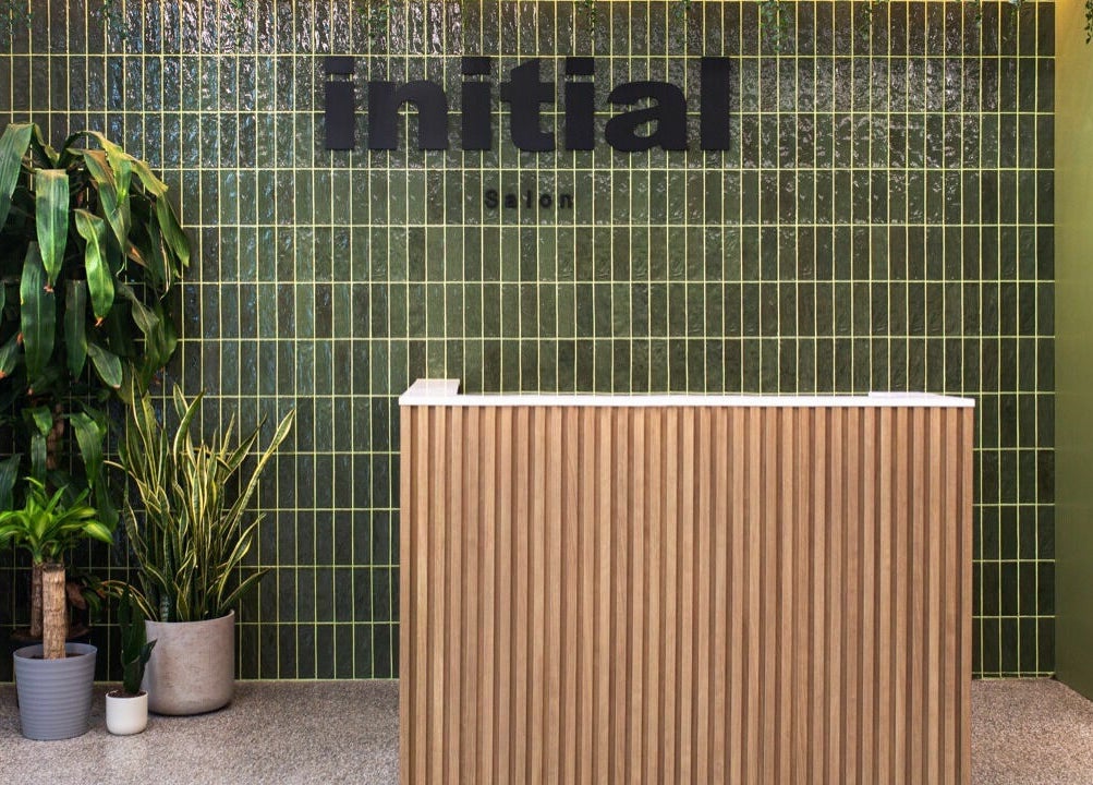 Reception area of Initial Salon in Richmond, British Columbia, CA with green tiles and potted plants.