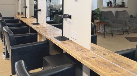 Chic salon interior at Niki Bartos Hairstylist, Norwich, England, GB, featuring modern black chairs and wooden stations.