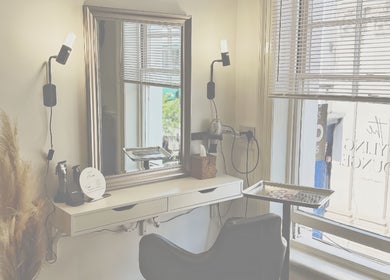 Elegant styling station at Niki Bartos Hairstylist in Norwich, England, GB, featuring a sleek mirror and comfy chair.