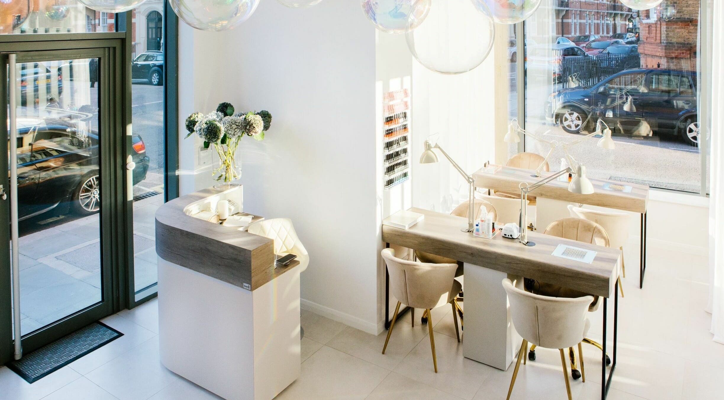 Bright, modern interior of Skin Loft, London, England, GB featuring elegant manicure stations and floral decor.