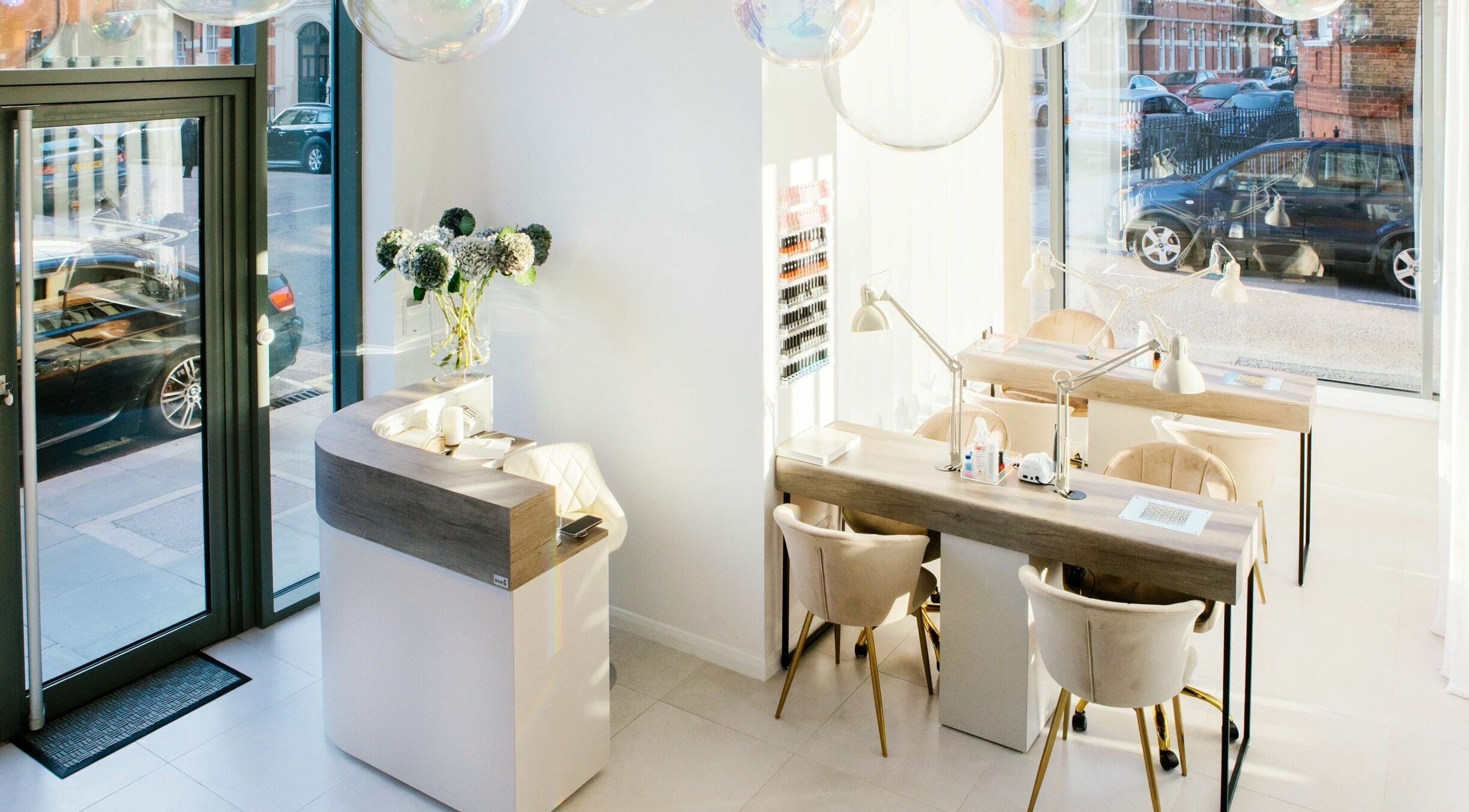 Bright, modern interior of Skin Loft, London, England, GB featuring elegant manicure stations and floral decor.
