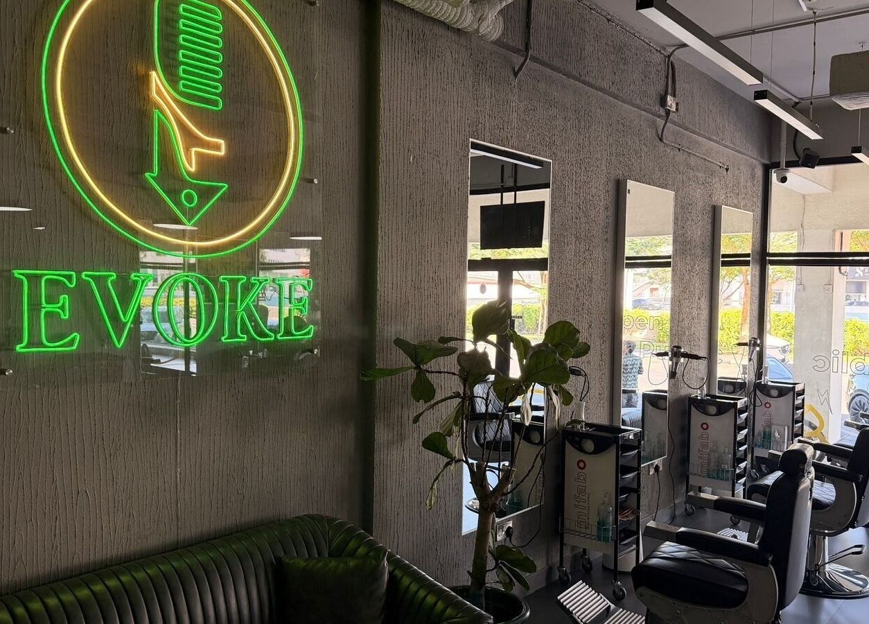 Interior of Evoke Gents Saloon in Dubai, AE showcasing neon sign and barber stations.