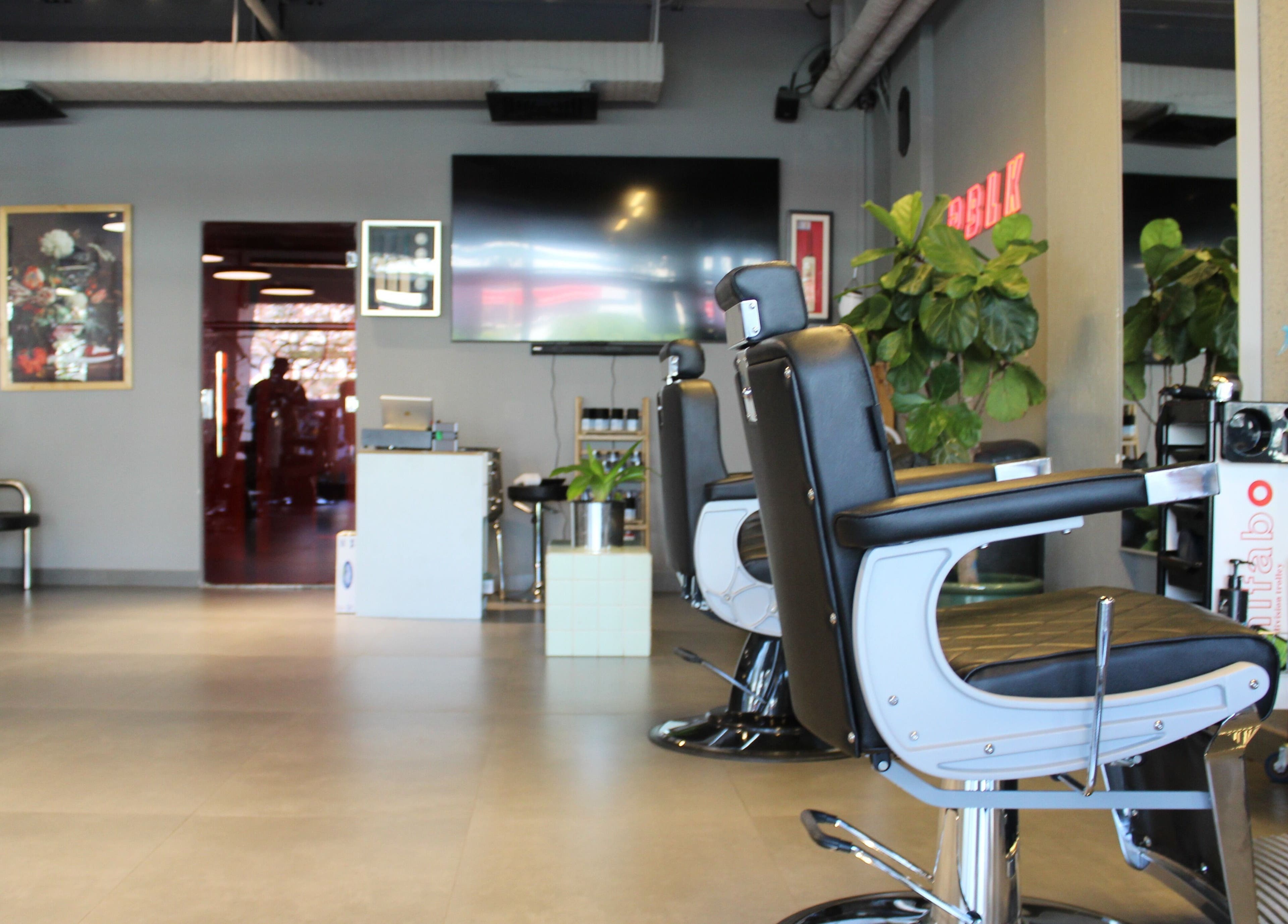 Modern interior of Evoke Gents Saloon in Dubai, AE showing sleek black styling chairs and vibrant decor.