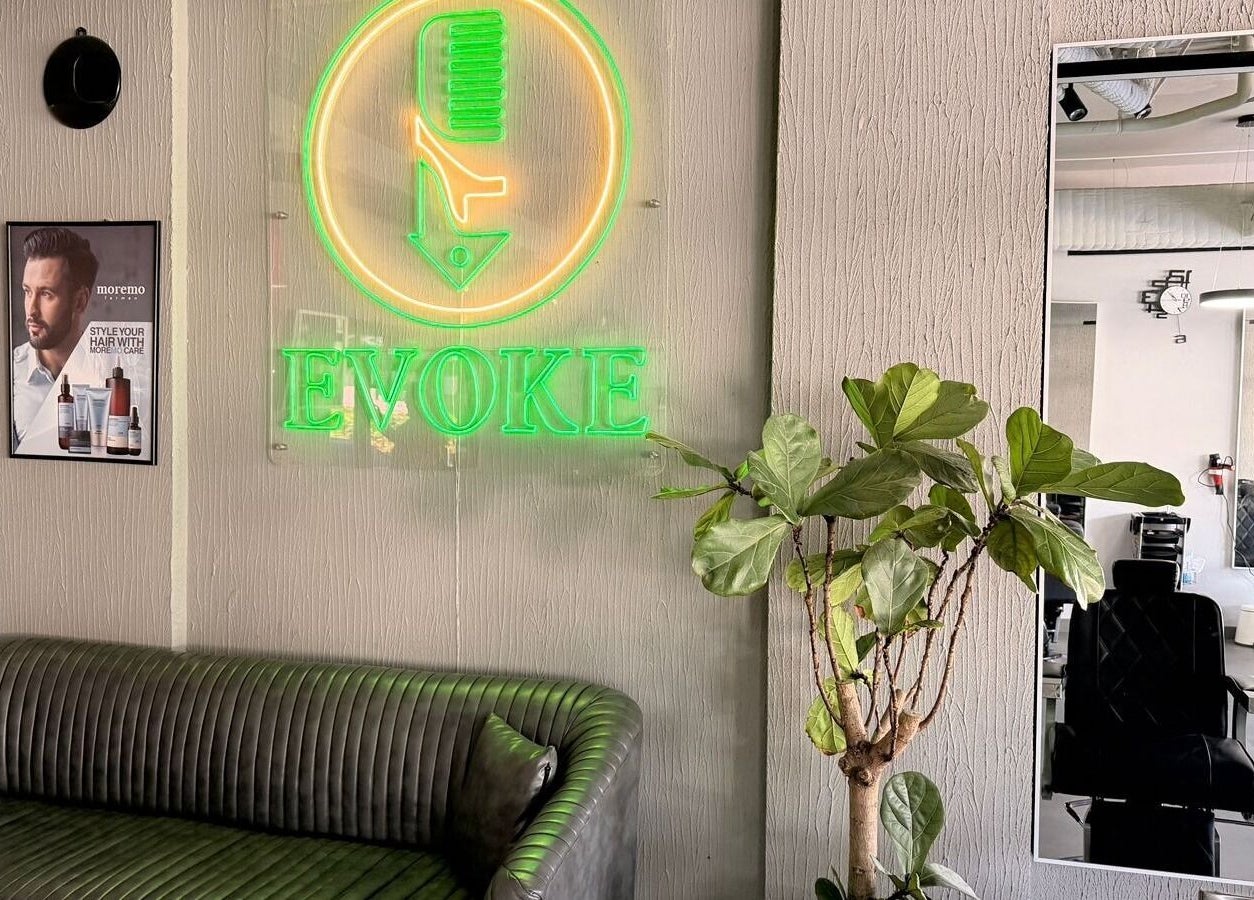 Chic lounge area at Evoke Gents Saloon in Dubai, AE, featuring a neon sign and sleek interior design.