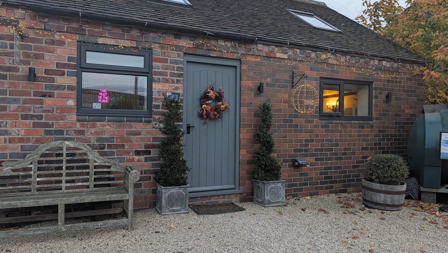 Charming brick exterior of The Beauty Barn at Pinwall in Atherstone, England, GB adorned with lights.