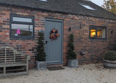 Charming brick exterior of The Beauty Barn at Pinwall in Atherstone, England, GB adorned with lights.