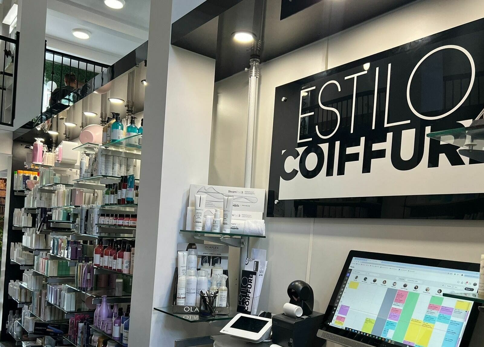 Intérieur moderne d'Estilo Coiffure à Québec, Québec, CA, avec produits de soins capillaires sur étagères élégantes.