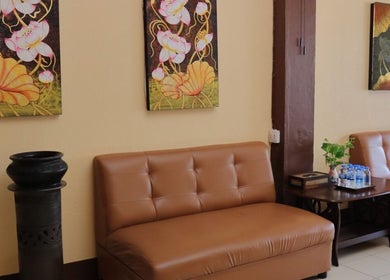 Elegant Kunlarat Massage lobby in Chiang Mai, Chiang Mai, TH with cozy sofa, artistic wall decor, and water bottles.