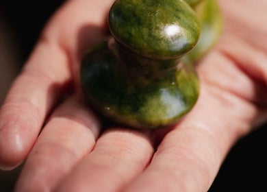 Hand holding jade massage tool at Big Calm Reflexology, London, England, GB.