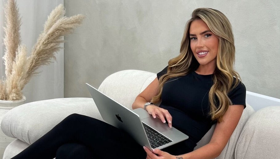 Woman with laptop at Luxury Locks Hair Extensions, Blackwater, England, GB showcasing chic modern style.