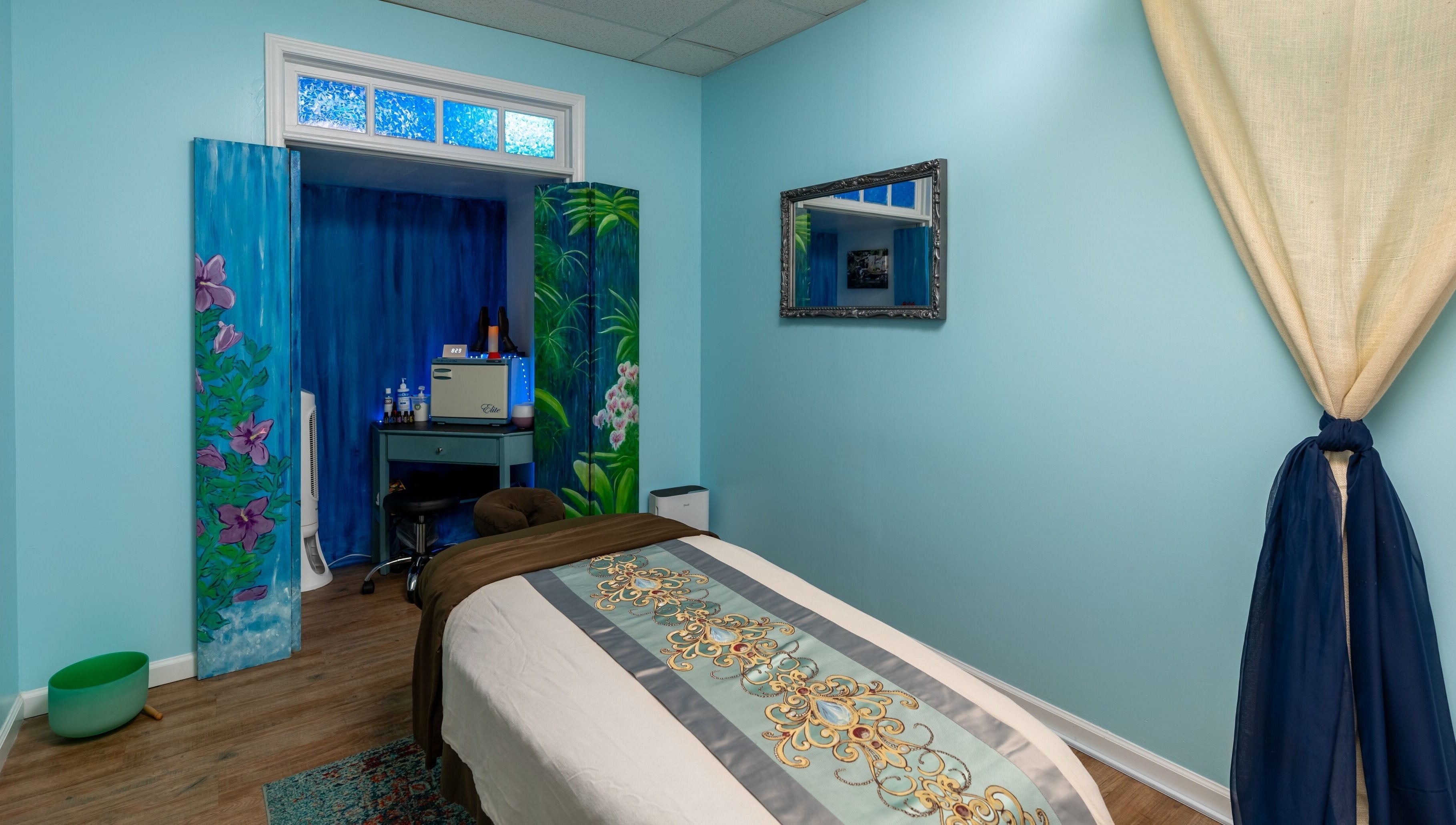 Tranquil massage room at Healing Hippie in Hampstead, North Carolina, US with soothing blue tones and floral decor.