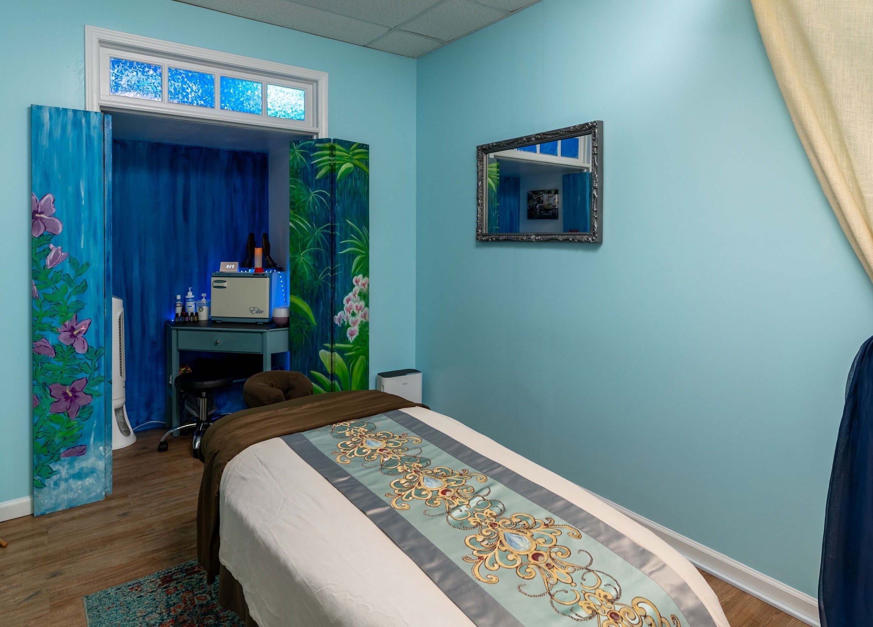 Tranquil massage room at Healing Hippie in Hampstead, North Carolina, US with soothing blue tones and floral decor.