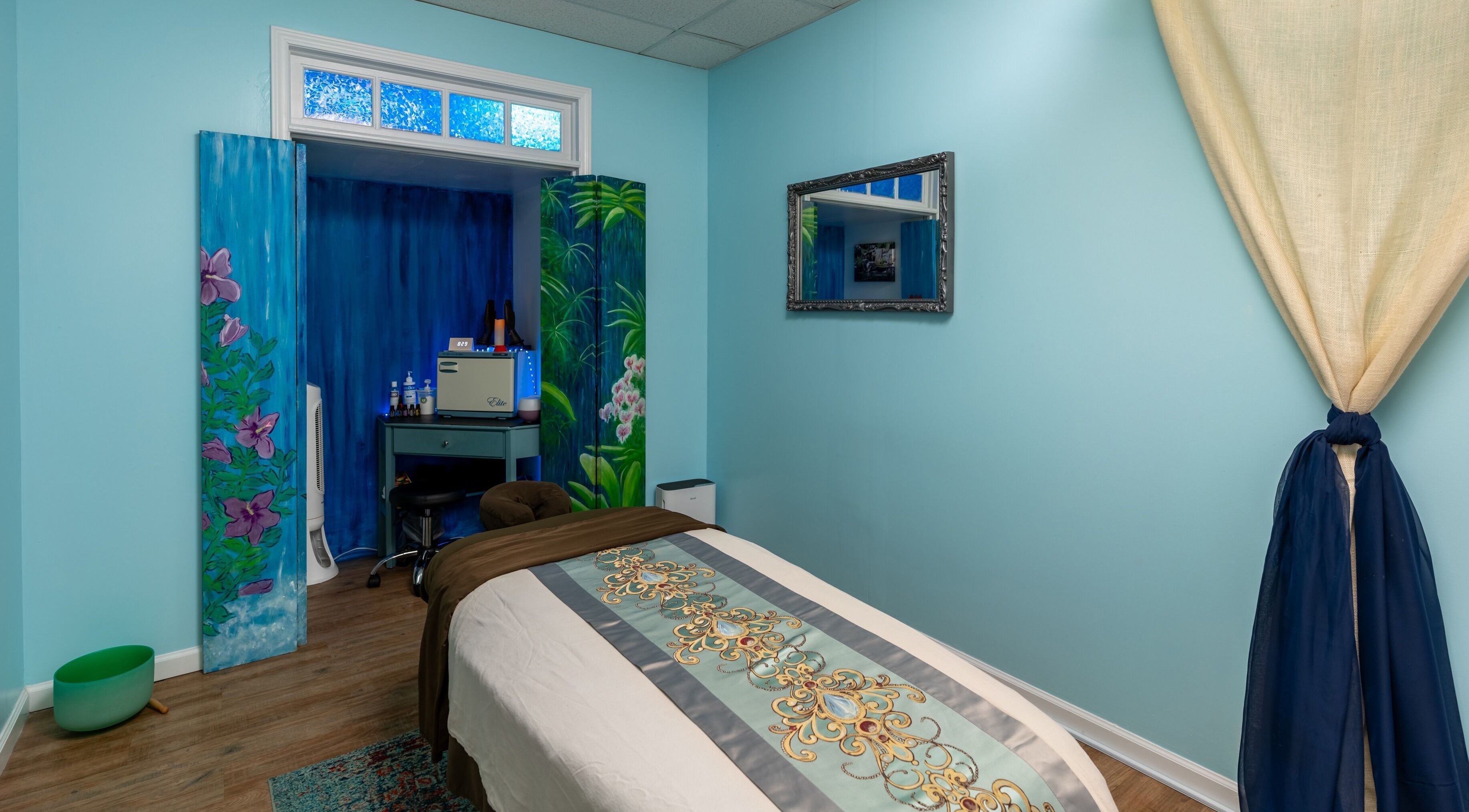 Tranquil massage room at Healing Hippie in Hampstead, North Carolina, US with soothing blue tones and floral decor.