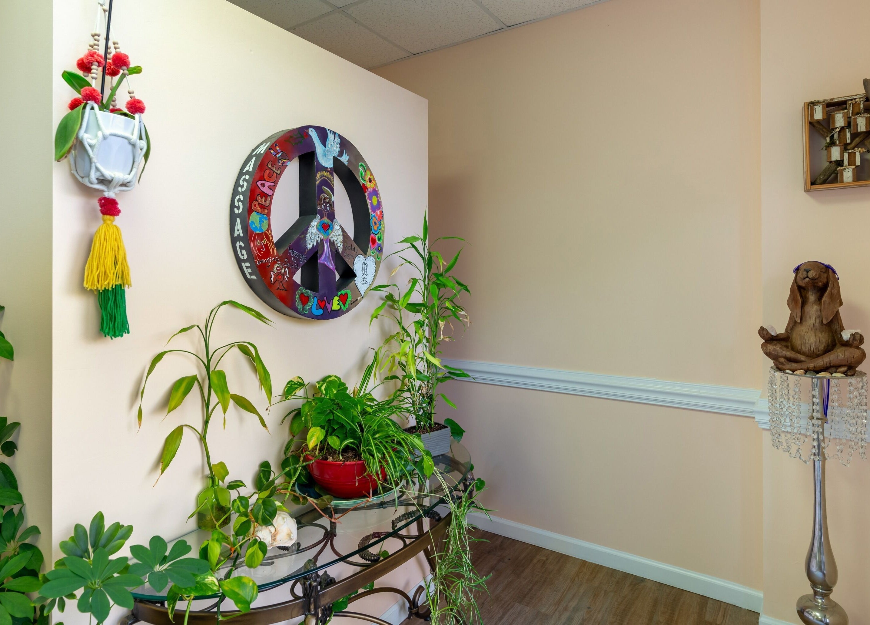 Vibrant peace-themed decor at Healing Hippie, Hampstead, North Carolina, US with lush plants and meditative sculpture.