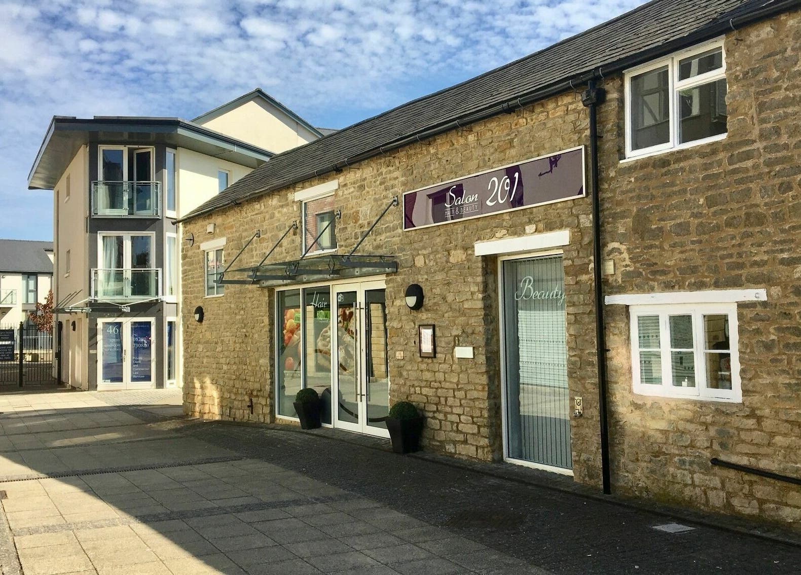Exterior of Hair beauty salon in Brackley, England, GB showcasing rustic stone facade and modern glass accents.