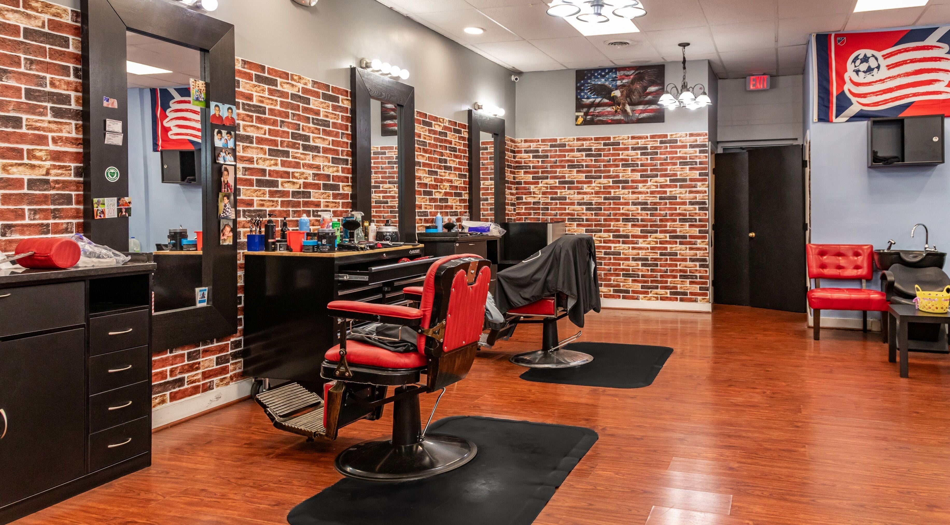 Stylish interior of Up Lift Barber Shop in Bellingham, Massachusetts, US with red chairs and brick walls.