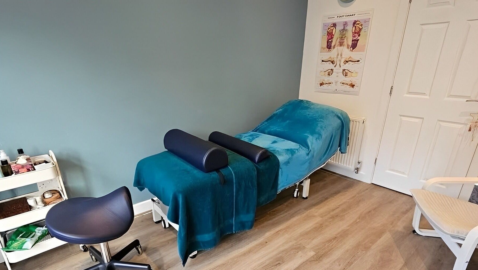 Therapy room at The Reflex Clinic, Newton Aycliffe, England featuring a blue treatment bed and chair.
