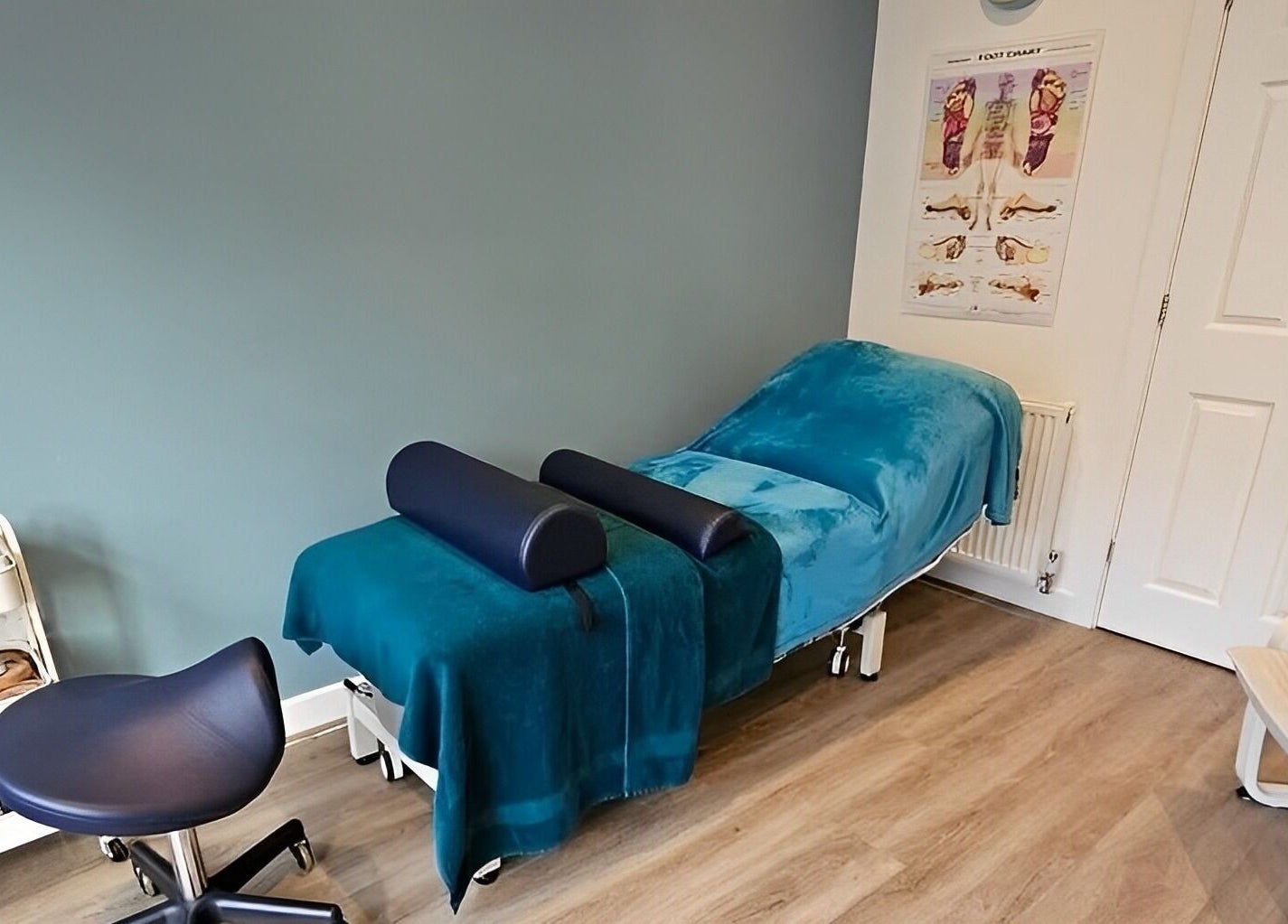 Therapy room at The Reflex Clinic, Newton Aycliffe, England featuring a blue treatment bed and chair.