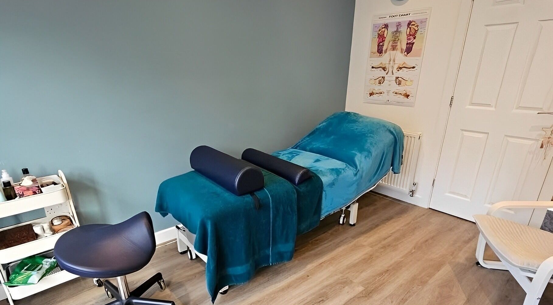 Therapy room at The Reflex Clinic, Newton Aycliffe, England featuring a blue treatment bed and chair.