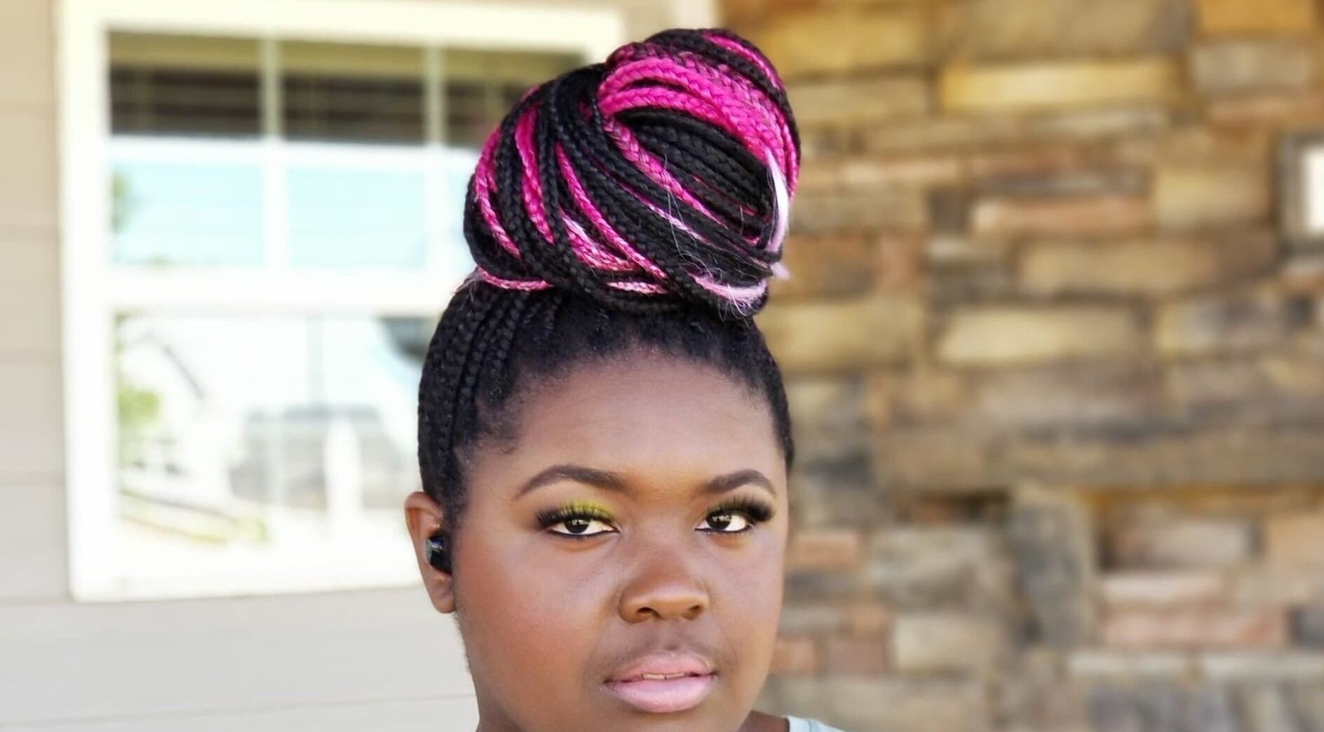 Stylish pink and black braided bun hairstyle from Bantu Hair Braiding & Beauty, Snellville, Georgia, US.