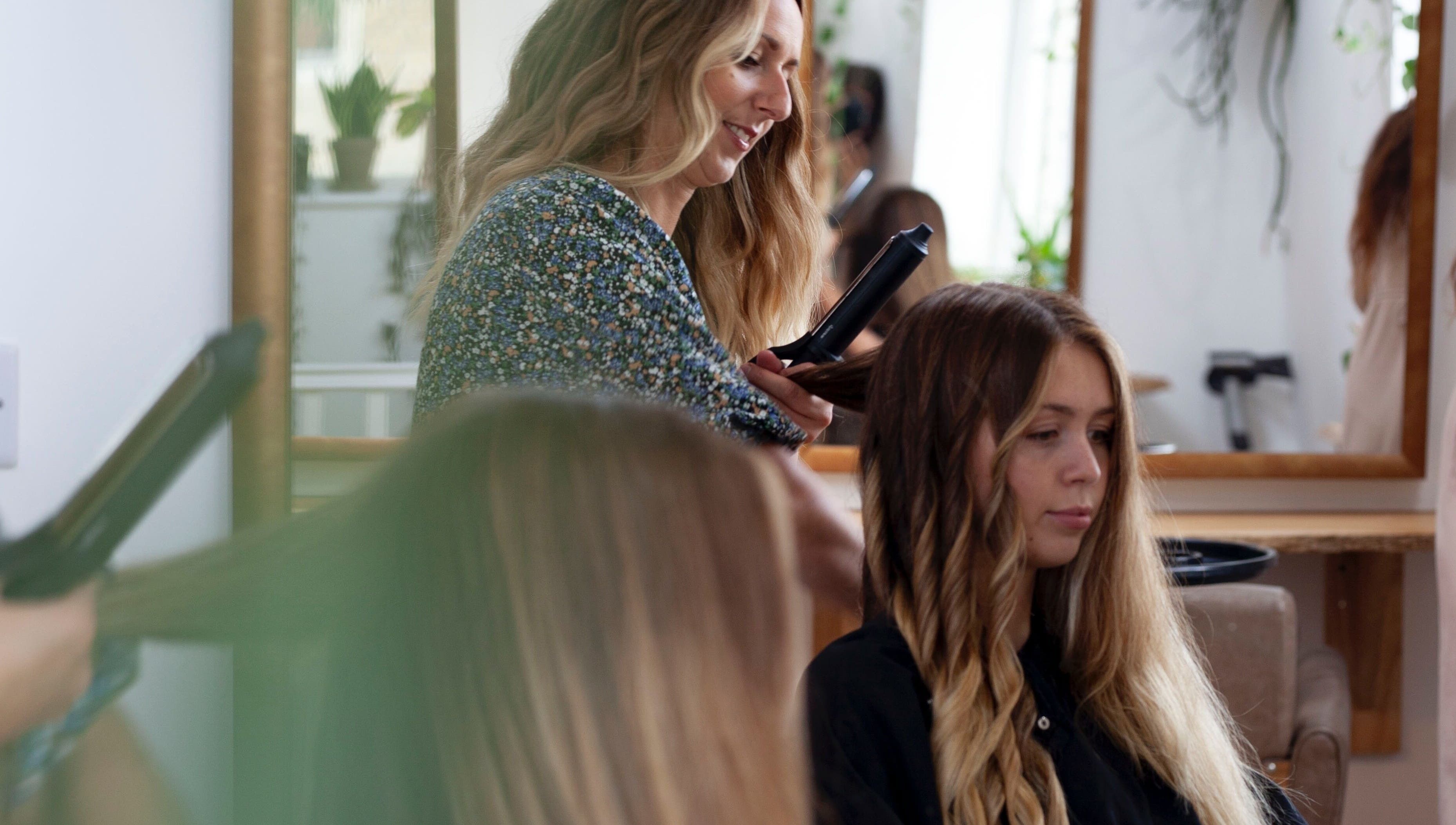 Hairstylist curling hair at Scarlett Collier Hair salon in Frome, England, GB.