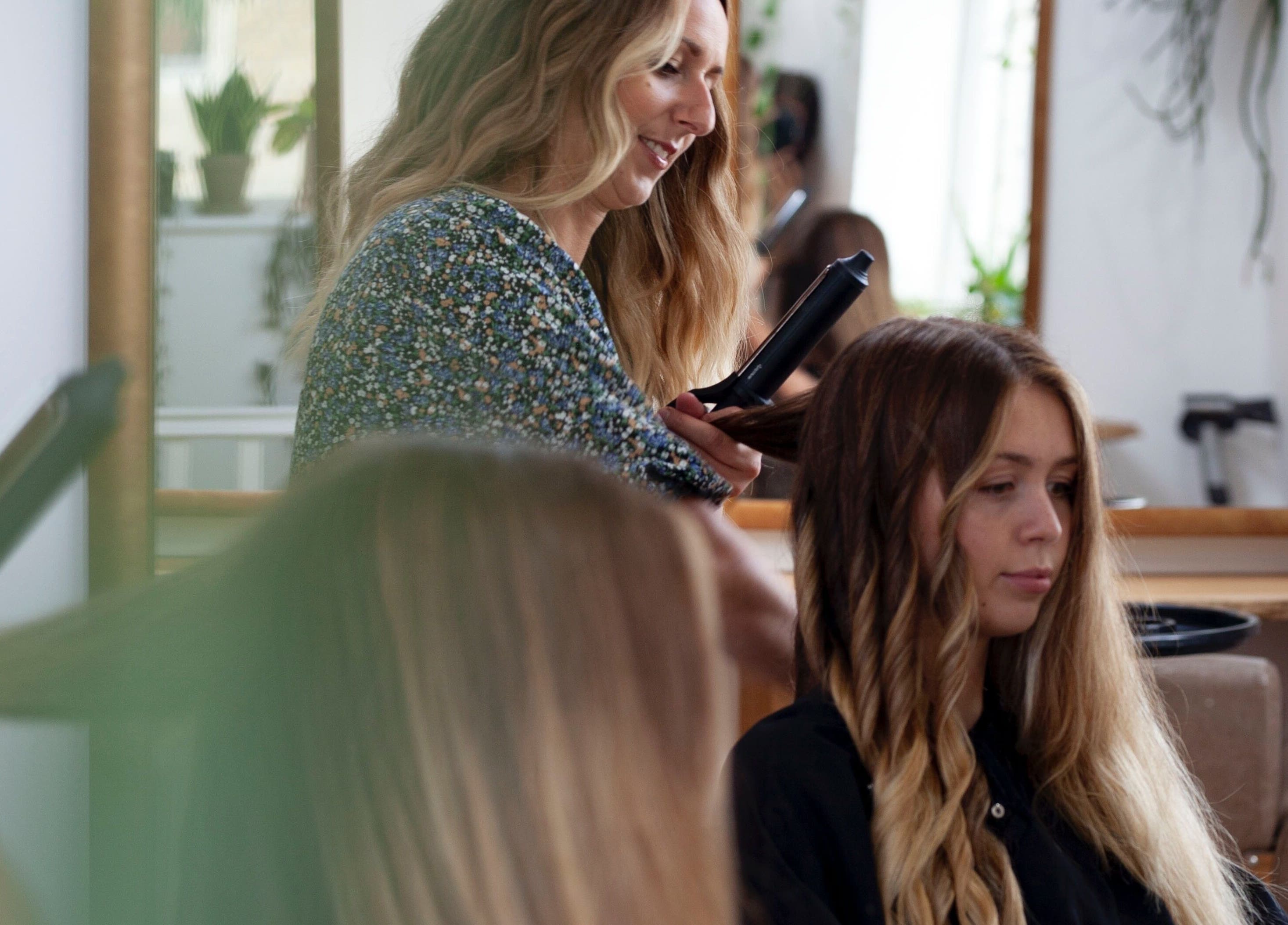 Hairstylist curling hair at Scarlett Collier Hair salon in Frome, England, GB.