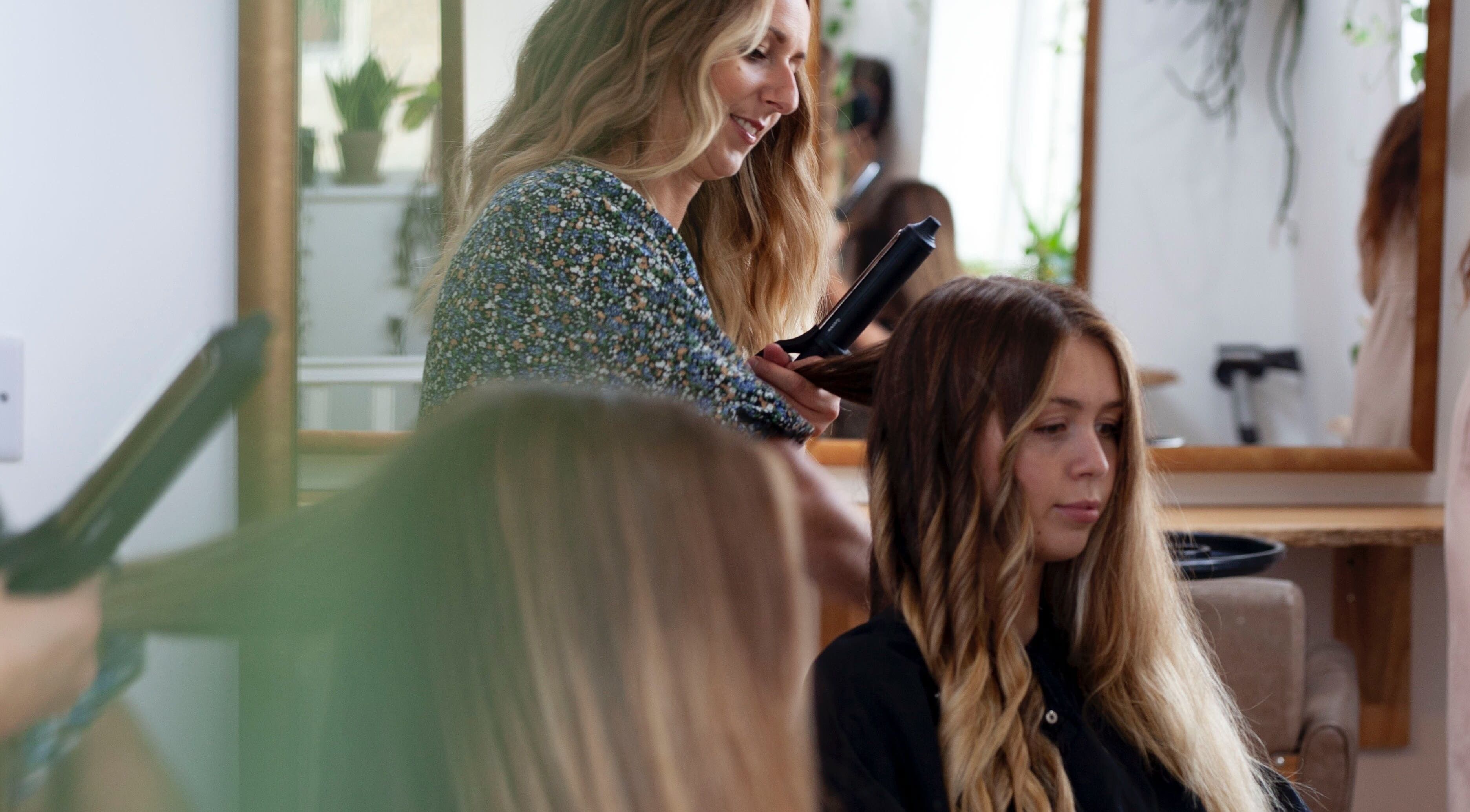Hairstylist curling hair at Scarlett Collier Hair salon in Frome, England, GB.