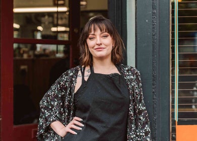 Smiling woman at Beck's Barbershop entrance, Portland, Oregon, US.