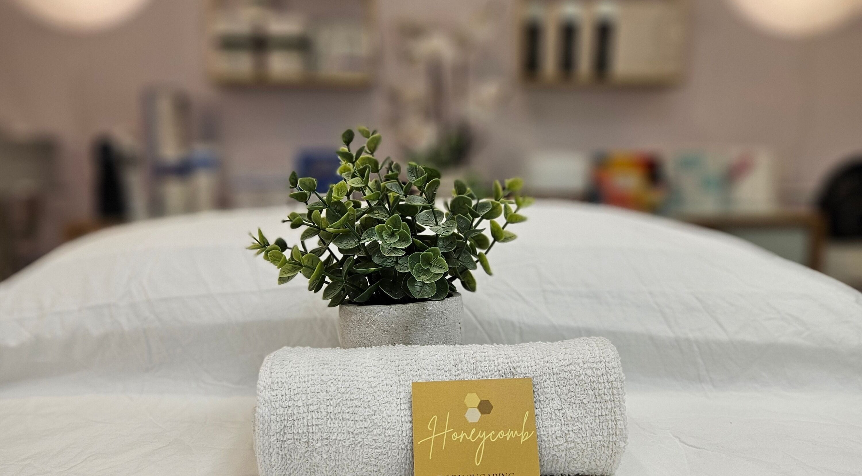 Spa setting with towel, greenery, and Honeycomb | Body Sugaring card in Burnaby, British Columbia, CA.