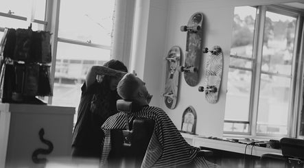 Modern barber at Head Honcho's Barbershop in Newton Abbot, England, GB, styling a client's hair.