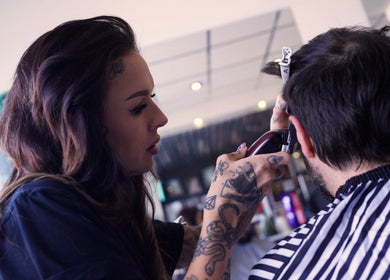 Tattooed stylist perfecting a haircut at Head Honcho's Barbershop/Salon, Newton Abbot, England, GB.