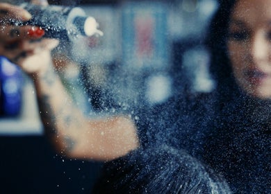 Hair stylist applying mist at Head Honcho's Barbershop/Salon in Newton Abbot, England, GB.