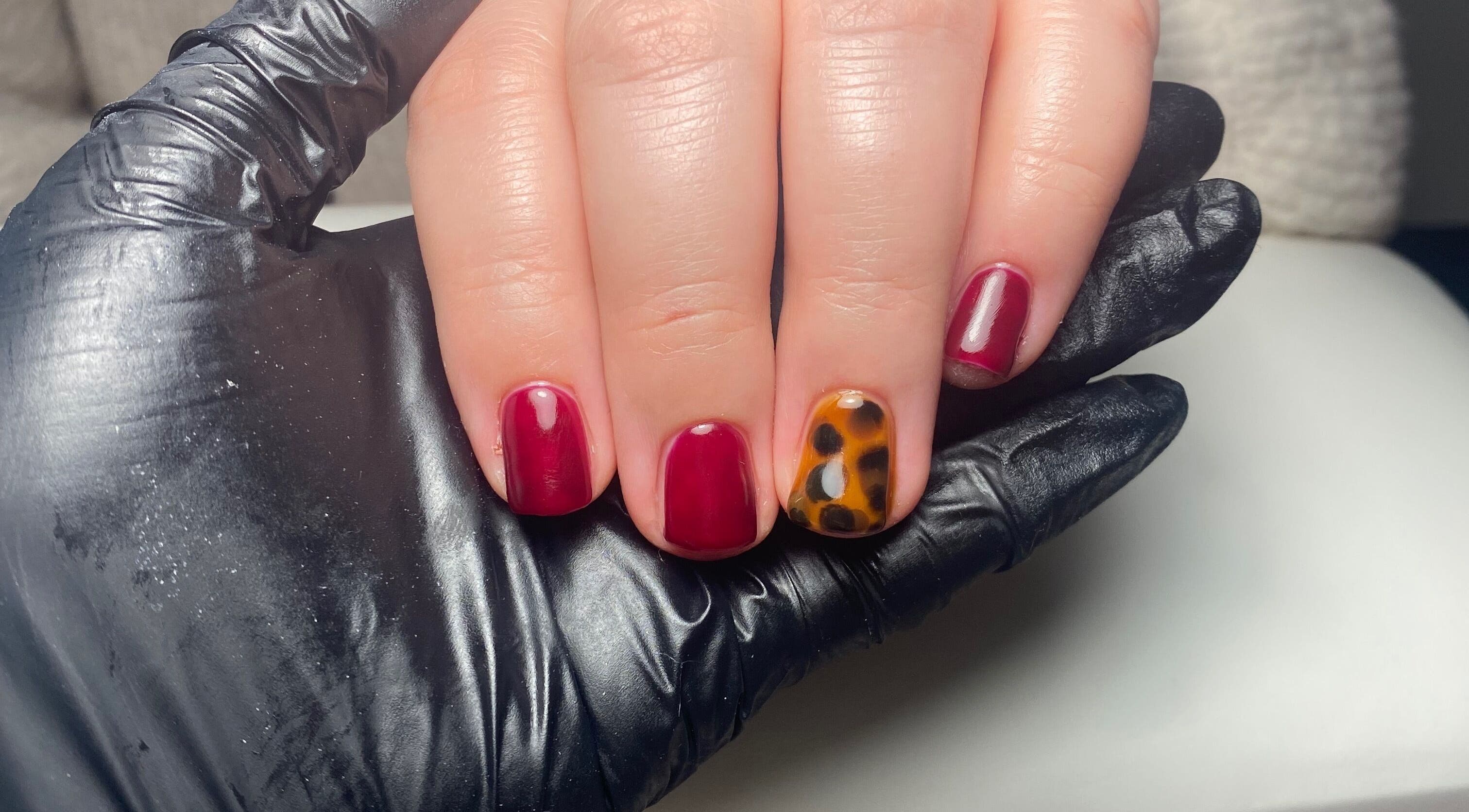 Stylish nail art at JD Nails in Telford, England, GB with rich red polish and accent cheetah design.