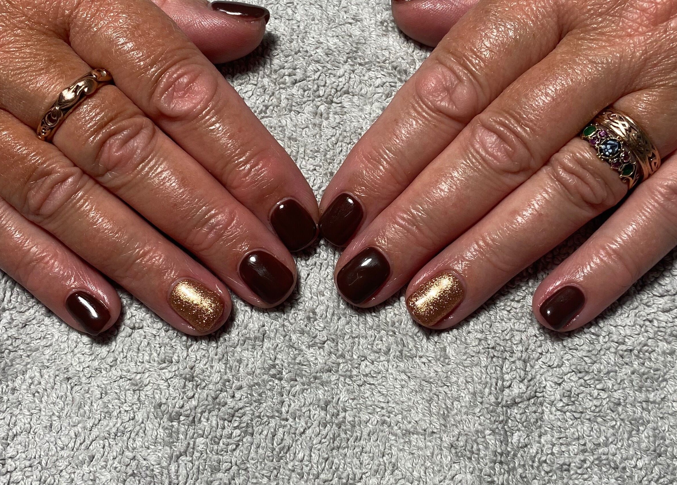 Elegant brown and gold nail art at JD Nails, Telford, England, GB on a soft gray towel.