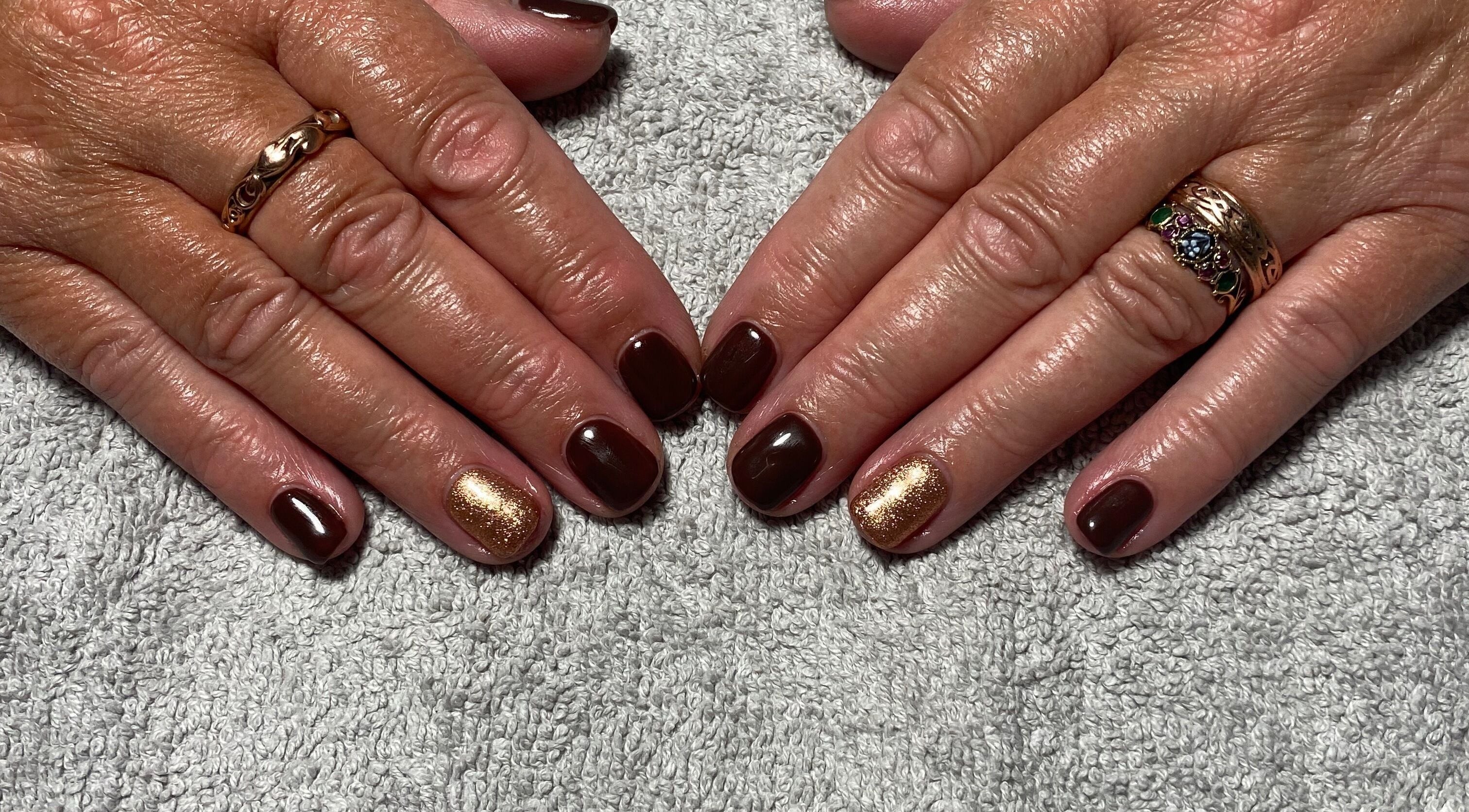Elegant brown and gold nail art at JD Nails, Telford, England, GB on a soft gray towel.