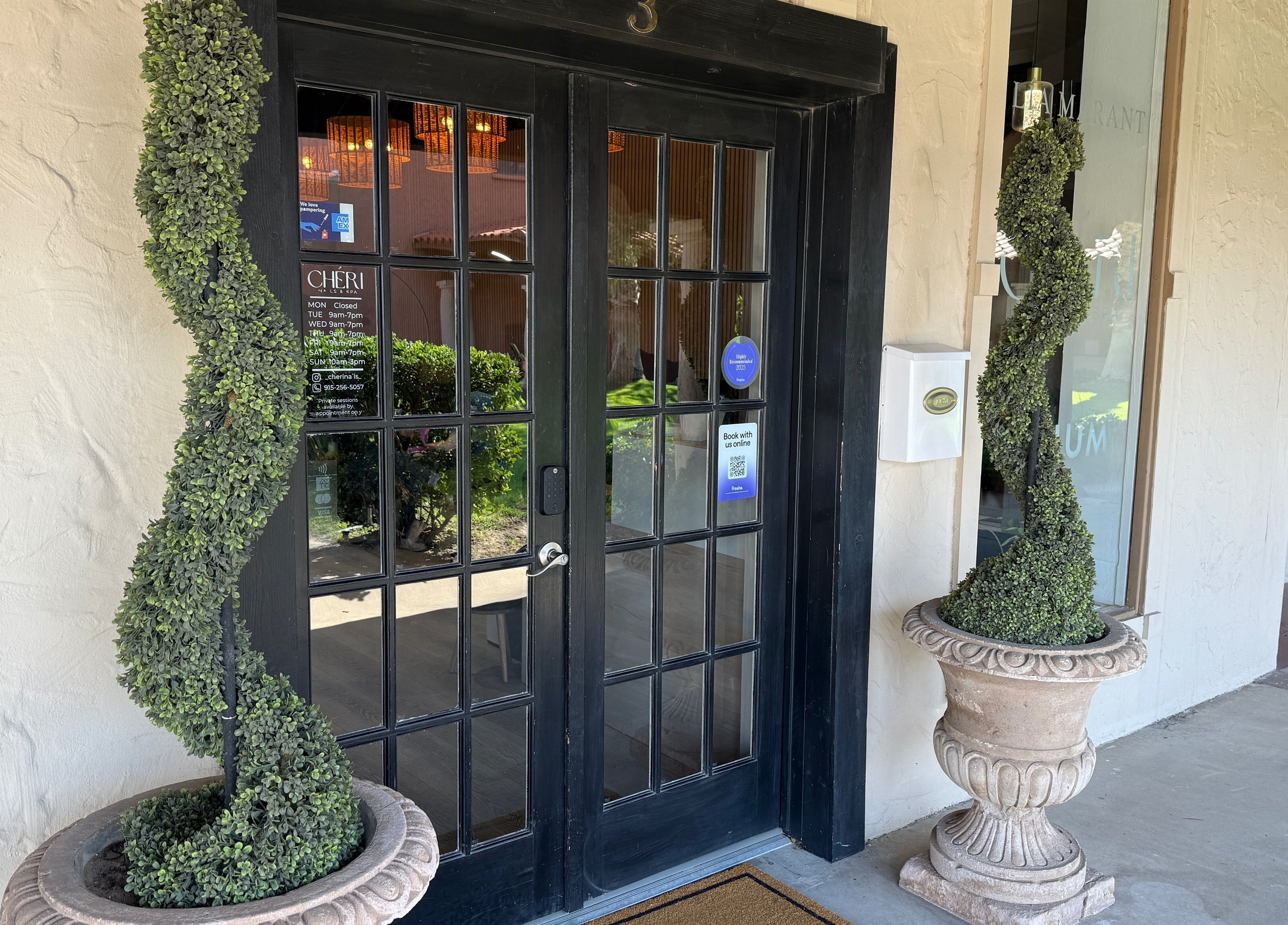 Front entrance of Chéri Nails and Spa, El Paso, Texas, US, adorned with topiary plants.